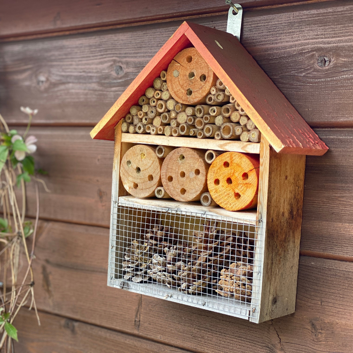 a bee hotel on a side of a wooden shed of the ground.